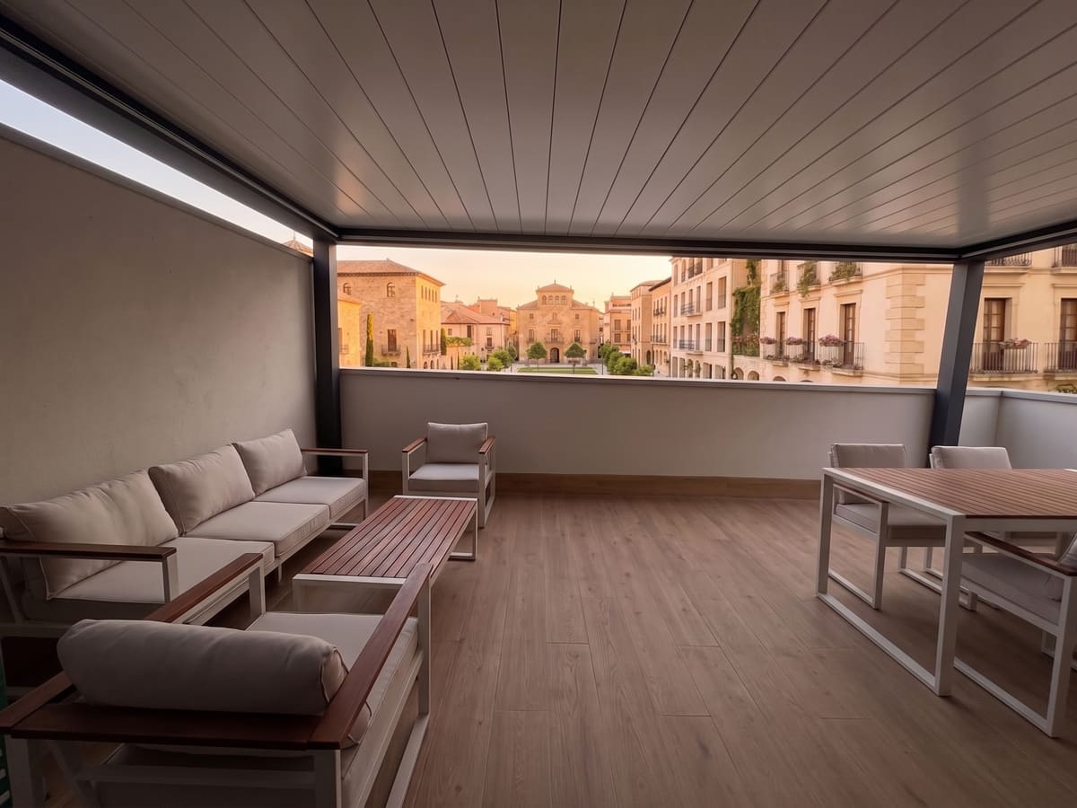 Pérgola bioclimática CERCA en la terraza de un ático, con vistas a la ciudad, a mediodía